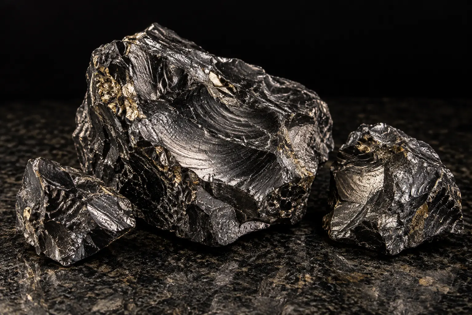 Frammenti di shungite Elite dal riflesso metallico su una pietra scura