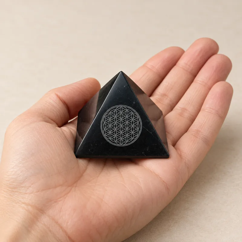 Piramide lucidata con Fiore della Vita inciso in shungite – in mano