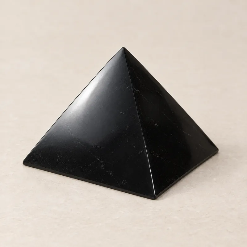 Piramide lucidata in shungite, su fondo chiaro